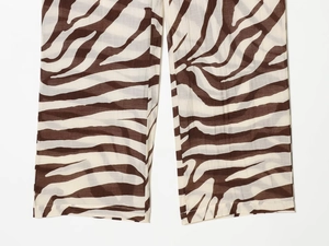 Détail de l'ourlet du pantalon zébré avec motifs marron foncé sur fond crème