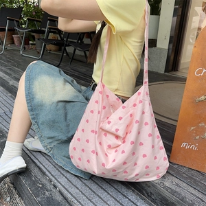 Close-up of pink heart pattern on durable canvas tote bag worn by a model outdoors