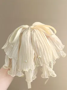 Detailed view of an off-white pleated fabric hair claw clip with pearls and ribbon