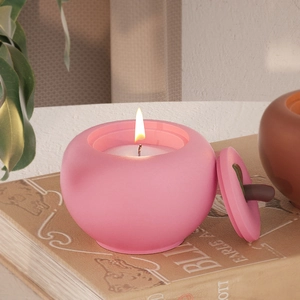 Roze perzikvormige kaarsenpot met blad deksel op vintage boeken in gezellige sfeer