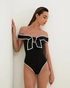 Detail of elegant black one-piece swimsuit with white contrast trim and large bow knot