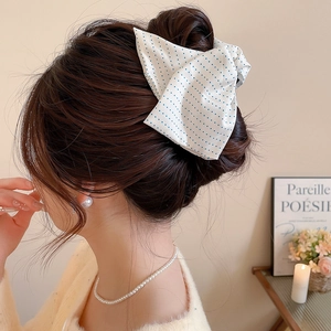 Detail of white polka dot fabric bow hair clip worn on a soft blonde hairstyle