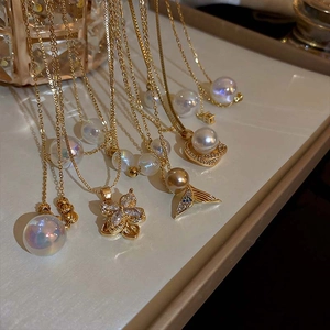 Golden titanium steel necklaces with pearl and fishtail pendants on beige leather