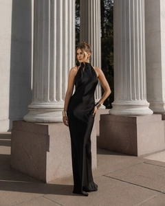 Elegant black satin halter maxi dress with backless detail against white stone columns