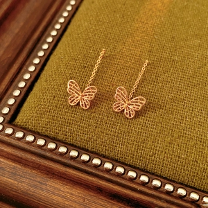 Macro shot of rose gold plated butterfly drop earrings with hollow filigree detail