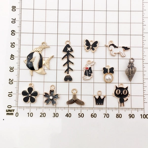 Detail view of assorted black and white enamel alloy charms on a metric grid ruler