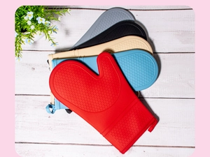 Five colored honeycomb silicone heat resistant oven mitts stacked on white wood surface