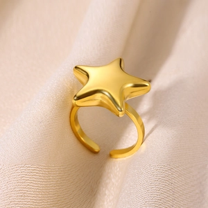 Macro shot of polished gold star shaped ring on textured fabric showing high gloss finish