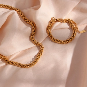 Detailed close-up of 18K gold-plated 6mm wheat chain jewelry set on pink silk fabric