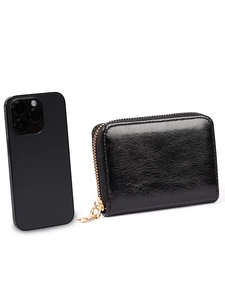 Compact black leather accordion card holder with gold zipper next to a smartphone for size