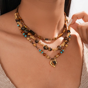 Macro detail of multi-layer Tiger Eye beaded necklace with heart pendant on golden chain