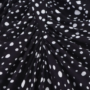 Macro shot of black chiffon fabric with white polka dots showing lightweight texture