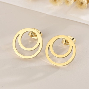 Macro shot of gold double circular earrings with polished finish on textured surface