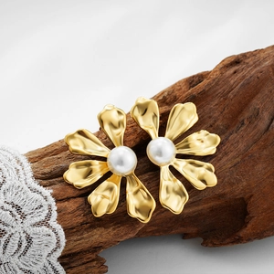Elegant matte gold flower earrings with central white pearl on a lace background