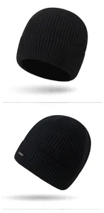 Close-up of black ribbed knit beanie featuring a silver rectangular brand metal plaque
