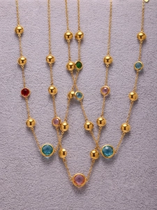 Detailed close-up of golden geometric chain necklace with vibrant round cut glass stones