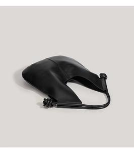 Detail of the minimalist black leather tote featuring unique decorative side knots