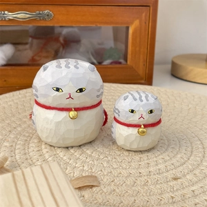 Detailed view of two hand-carved wooden cat figurines with red collars and golden bells