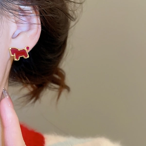 Close-up of red zircon puppy stud earring with golden beaded edge on model's ear