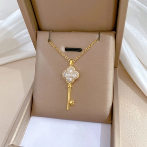 Golden four-leaf clover key necklace with sparkling crystals in a luxury jewelry box