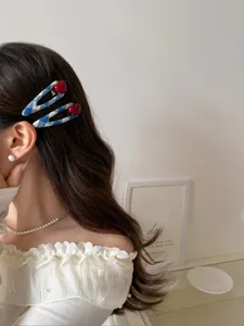 Close-up of blue and white checkered hair clips with red heart accents on long wavy hair