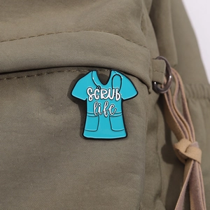 Detailed view of Scrub Life enamel pin pinned onto an olive green canvas bag