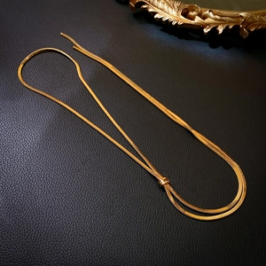 Detail of adjustable gold snake chain necklace with slider clasp on black leather