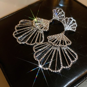 Macro shot of silver fan-shaped earrings with full rhinestones on black leather base