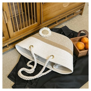 Detail of woven straw tote bag with floral applique and knotted rope handles