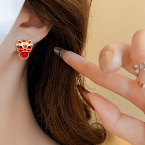 Detailed view of red enamel lion dance earrings with a pearl bead tassel on ear