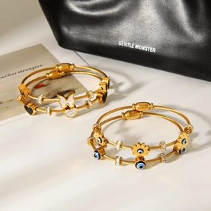 Detail of gold-plated steel wire bracelets with butterfly, evil eye, and heart charms