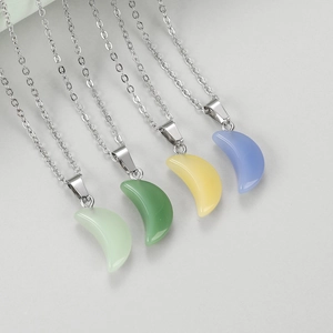 Detail van vier halve maan hangers van hars aan zilveren kettingen in diverse pastelkleuren