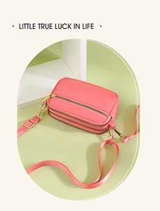 Close-up of triple zipper pockets on coral crossbody bag with gold hardware details