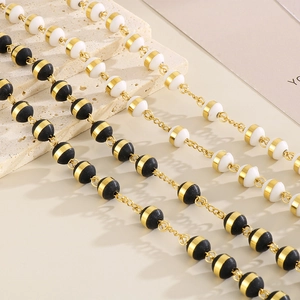 Detail of black and white beads with gold rings on a stainless steel rosary necklace