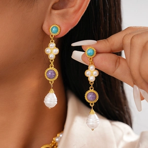 Detail of vintage gold drop earring with turquoise bead, purple gemstone and baroque pearl