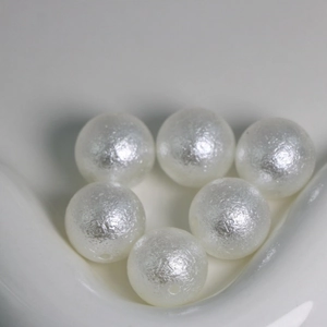 Macro shot of white textured ABS imitation pearl beads with holes for DIY jewelry