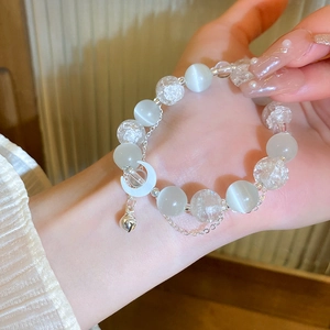 Detail of beaded bracelet with white cat-eye stones, clear crystals and moon charm
