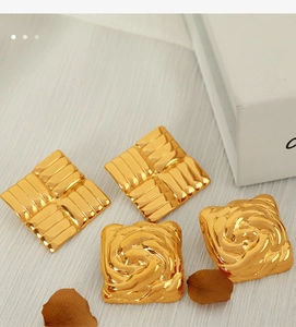Nahaufnahme von quadratischen Vintage-Ohrsteckern aus Gold-Titanstahl mit Textur