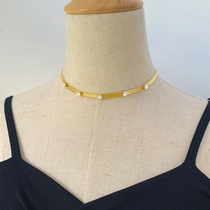 Gold herringbone chain necklace with inset cubic zirconia crystals on a neck mannequin
