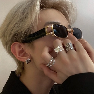 Chic gold-frame rectangular sunglasses and silver letter rings worn by a model