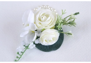 Detailed macro view of wedding boutonniere featuring white roses and green leaf textures