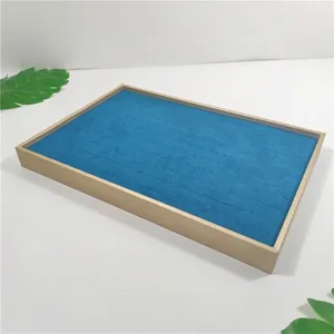 Detail of 100-slot jewelry display tray with navy velvet lining and beige textured frame