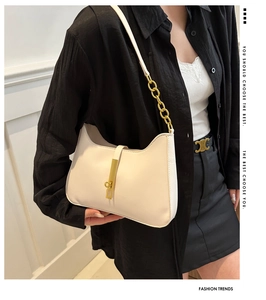 Detail view of cream shoulder bag with gold chain strap and vertical metal clasp closure