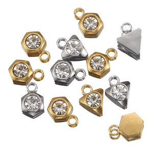 Dettaglio macro di pendenti in metallo a esagono e triangolo dorati e argento con strass