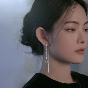 Elegant silver star and moon tassel drop earrings worn by a model in a side view