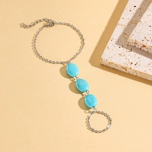 Close-up of silver finger bracelet featuring three blue turquoise stones on stone decor