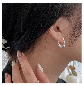 Close-up of elegant S925 sterling silver twisted hoop earring on a female model