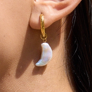 Detailed close-up of 18K gold hoop earring featuring a white crescent pearl pendant