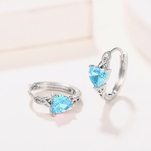 Macro detail of heart-shaped light blue gemstone earrings with celtic knot silver design