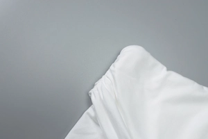 Close-up of white textile fabric showing detailed stitching and soft material texture